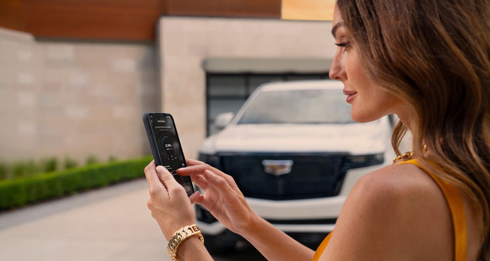 lady checking her mobile with a Cadillac vehicle background | Cadillac of Rexburg in Rexburg ID